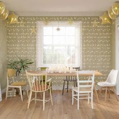 a dining room table and chairs with lights on the wall behind them in front of a window