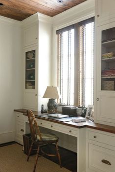 a chair sitting in front of a desk with a lamp on top of it next to a window