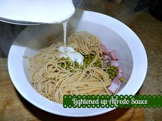 someone is pouring milk over some noodles in a white bowl on a wooden table top