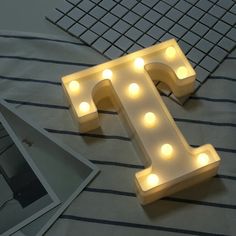 a light up letter that is sitting on top of a bed next to a photo