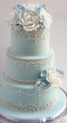 a three tiered blue wedding cake with white flowers