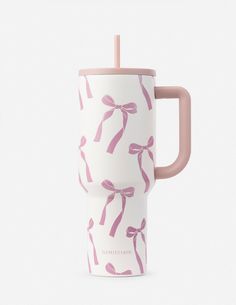 a pink and white coffee cup with a handle on the side, decorated with bows