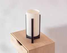 a white and black vase sitting on top of a wooden table next to a drawer