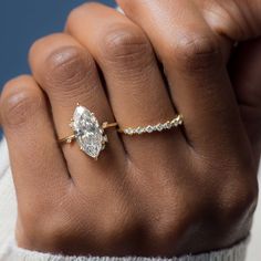 a woman's hand wearing a gold ring with a diamond in the middle and an engagement band