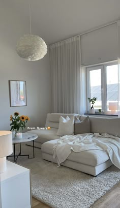 a living room with a large white couch and rug on the floor next to a window