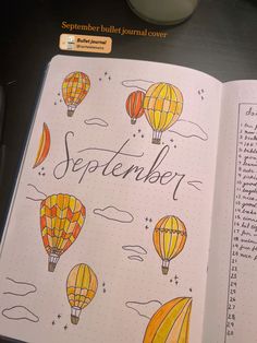 an open notebook with hot air balloons and the words september written on it in cursive writing