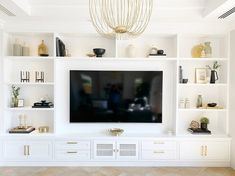 a white entertainment center with shelves and a flat screen tv mounted on it's wall