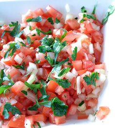 a white bowl filled with chopped tomatoes and herbs