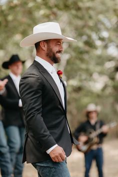 a man in a suit and hat standing next to another man wearing a cowboy hat