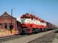 a red and white train traveling down tracks next to a building