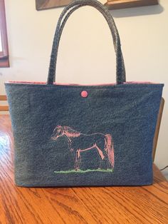 a bag with a horse drawn on it sitting on top of a wooden table next to a wall