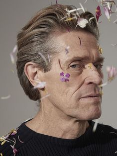 an older man with flowers on his forehead and eyes are surrounded by confetti