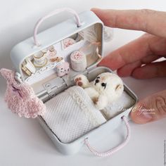 a small white teddy bear in a miniature suitcase