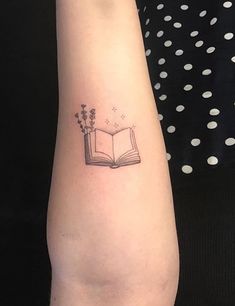 a woman's arm with a book and flowers tattoo on the left side of her arm