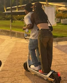 two people riding on a scooter in the street