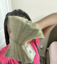 a woman in pink shirt holding money up to her face