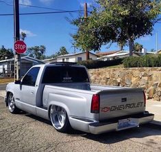 a silver chevrolet truck parked in front of a stop sign