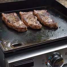 three steaks cooking on top of a grill