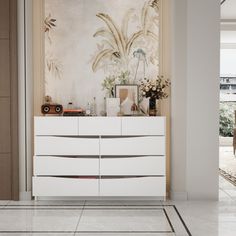 a white dresser sitting in the middle of a room next to a painting on the wall