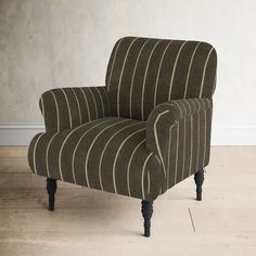 a striped chair sitting on top of a hard wood floor next to a white wall