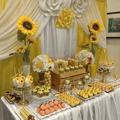 a table with sunflowers, cupcakes and other desserts on it