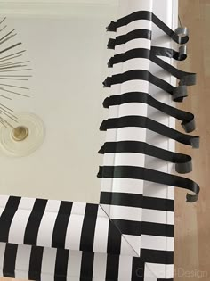 a black and white striped curtain hanging on the side of a wall next to a clock