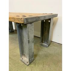 a bench made out of metal pipes and wooden planks in a room with concrete flooring