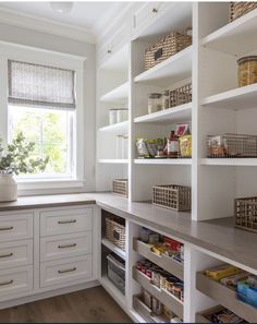 an organized pantry with white cabinets and drawers