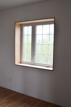 an empty room with a window and hard wood floor