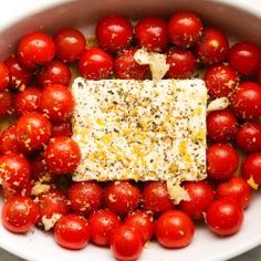 tomatoes and cheese in a white bowl with seasoning on top for garnish