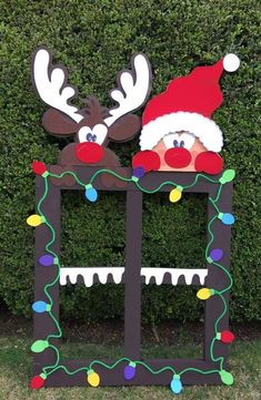 two reindeers with hats and lights on their heads are standing in front of a hedge