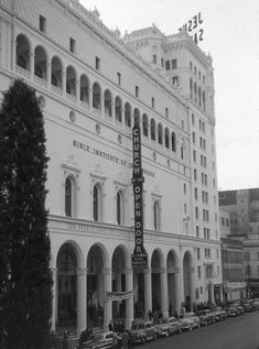 an old black and white photo of a building with cars parked in front of it