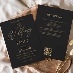 two black and gold wedding cards on top of a wooden plate with dried flowers in the background