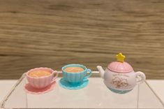 two tea cups and a saucer on a clear tray