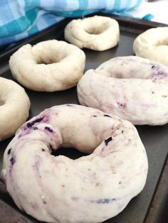 four doughnuts sitting on top of a baking pan covered in blueberry sauce