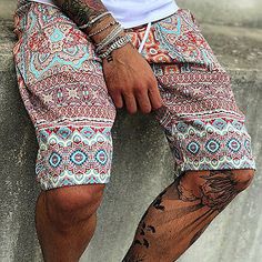 a man with tattoos sitting on top of a cement wall