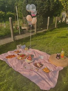 a picnic with balloons and food on the grass