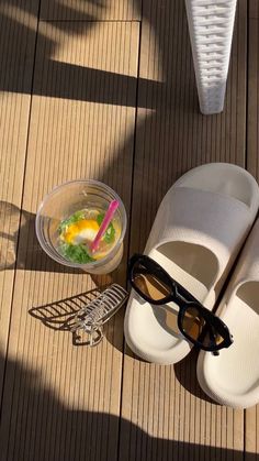 a pair of white shoes sitting on top of a wooden floor next to a bowl of food