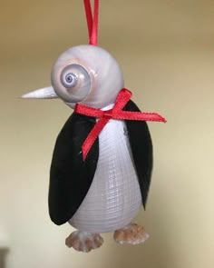 an ornament shaped like a penguin with a red ribbon on it's neck