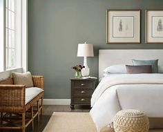 a bedroom with gray walls and white bedding, two framed pictures on the wall