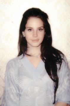 an old photo of a woman with long dark hair and blue shirt posing for the camera