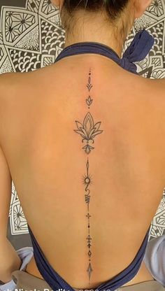 the back of a woman's neck with a flower tattoo on her lower back