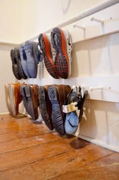 several pairs of shoes are hanging on the wall next to a pair of shoe rack