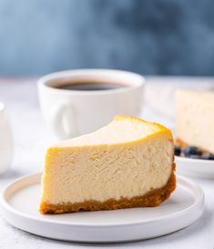 a piece of cheesecake on a plate with a cup of coffee in the background