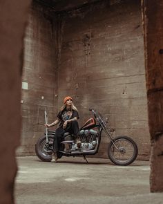 a woman sitting on top of a motorcycle in an old building with exposed concrete walls