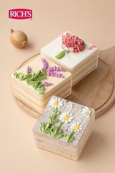 two small cakes with flowers on them sitting on a wooden platter next to an acorn