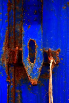 an old rusted blue door with a rope hanging from it's center hole