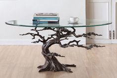 a glass table topped with books and a tree branch design on top of wooden flooring