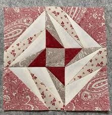 a red and white quilted square on top of a gray carpet with an ornament in the center