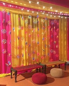 the room is decorated in bright colors and has two benches on one side, with lights strung from the ceiling